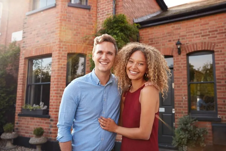 Couple standing in front of a brick home