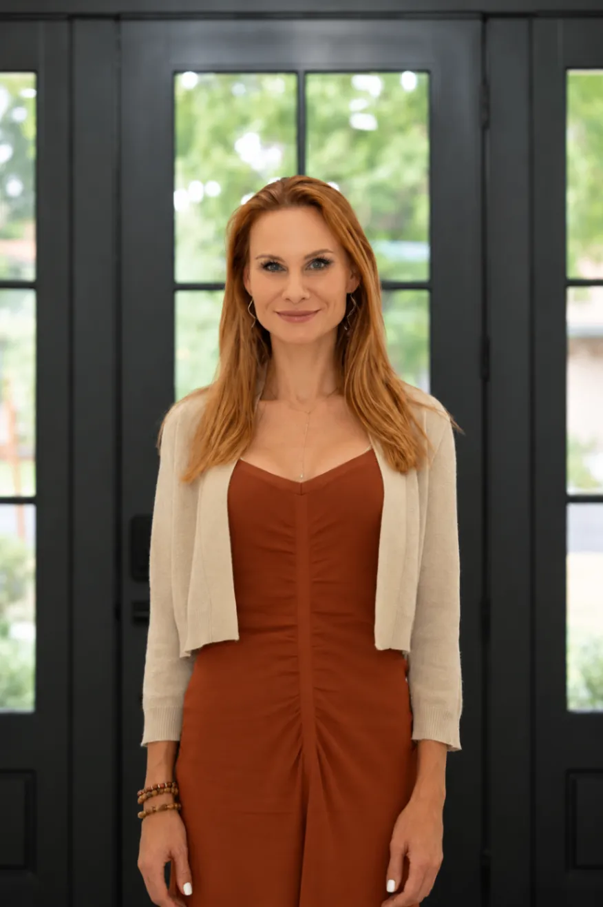 Kristina Cat in a rust-brown dress and cream jacket